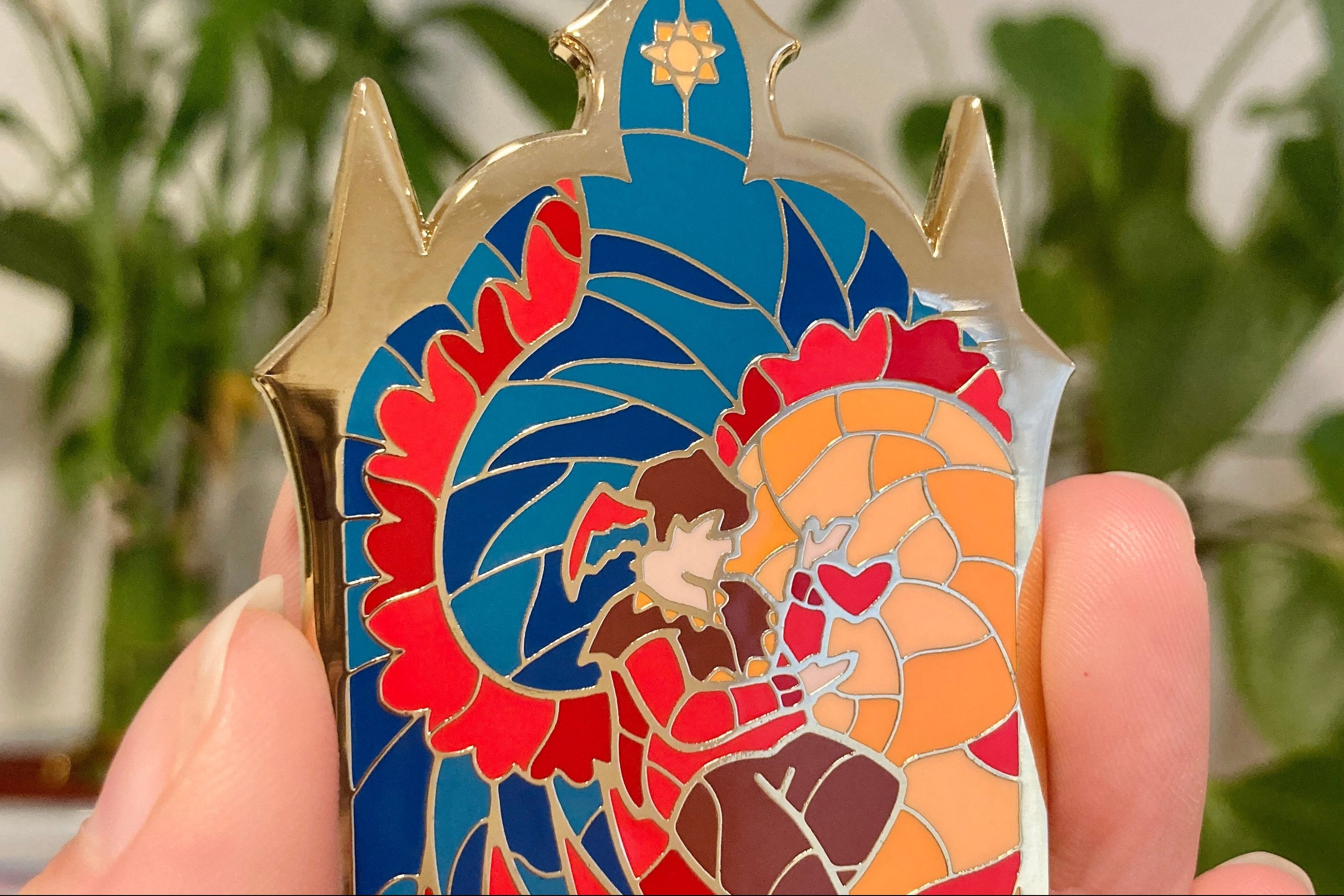 Colorful enamel pin with a design of a character in a stained glass window style held in a hand.